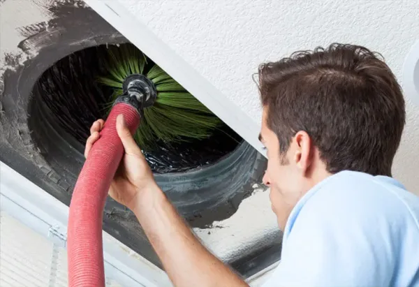 Technician cleaning air ducts with professional brush and vacuum equipment